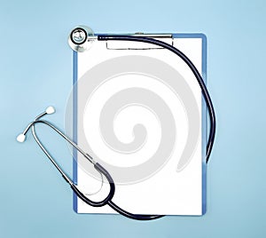 Flat lay of stethoscope and writing pad paper clip board on light blue background with copy space, healthcare and medical concept