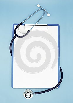 Flat lay of stethoscope and writing pad paper clip board on light blue background with copy space, healthcare and medical concept