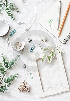 Flat lay still life of homemade crafts work table with accessories - wooden photo frame, flowers, seashells, paper clips, notebook