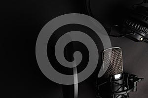 Flat lay, Studio microphone with pop filter and professional headphones. Black on a black background. Podcasts, radio, streams