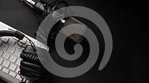 Flat lay, Studio microphone with professional headphones on a PC keyboard. Black on a black background. Podcasts, radio, streams,