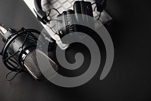 Flat lay, Studio microphone with professional headphones on a PC keyboard. Black on a black background. Podcasts, radio, streams,