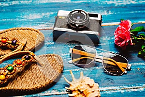Flat lay of summer fashion with camera slippers sunglasses and other girl accessories on blue background