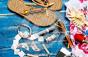 Flat lay of summer fashion with camera slippers sunglasses and other girl accessories on blue background