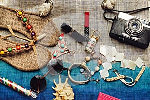 Flat lay of summer fashion with camera, slippers, sunglasses and other girl accessories on top of the bag as background