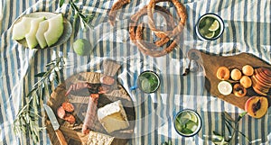 Picnic set with fruit, cheese, toast, honey, wine with a wicker basket and a blanket. Beautiful summer background with