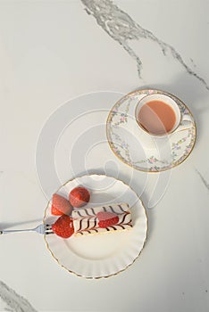 Flat lay with summer time fresh cream slice cake with strawberries and tea