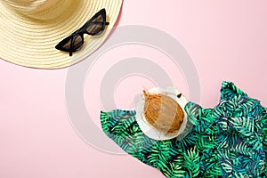 Flat lay summer women`s accessories and coconut on pastel pink background with blank space for text. Top view travel or vacation