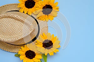 Flat lay with sunglasses, straw boater hat and bright big yellow sunflower on blue background. Travel summer concept. Copy space