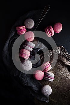 Flat-lay of sweet pink, violet french macaroon cookies on black slate plate