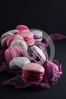 Flat-lay of sweet pink, violet french macaroon cookies on black slate plate