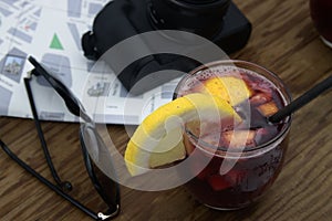 Flat lay of a table with a glass of sangria, a map and a camera