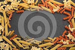 Flat lay of a table with Italian pasta of different varieties and colors (penne, short mafalda, fusilli