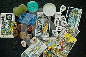 flat lay of Tarort cards, runes, astrologycal symbols and crystals on a black background