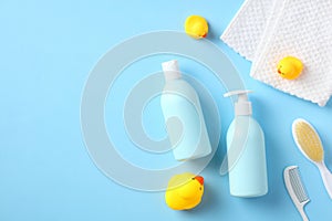 Flat lay, top view baby shampoo bottle, body wash gel, towel, hair comb, brush, yellow rubber ducks on blue background. Baby