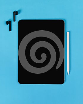 Flat lay top view blank screen digital tablet on blue background. Home office workspace