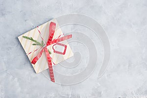 Flat lay top view christma gift withred ribbon an blank tag on grey concrete table. New year