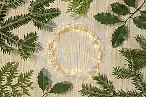 Flat lay top view, Christmas background circle shape border frame, light garland and fir twigs wooden background