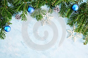 flat lay top view christmas tree branches frame with silver toys and fir-cones on blue background. New year holiday concepr. Text