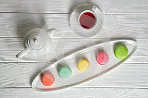 Flat lay, top view. Close up. Provence breakfast. Colorful pastry macarons laid out on an oblong plate, a cup of berry tea.