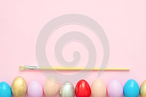 Flat lay top view colorful easter egg painted in pastel colors composition with paint brush on pink pastel color background.