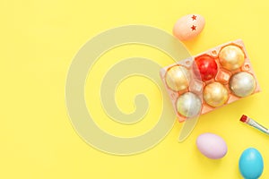 Flat lay top view colorful easter egg painted in pastel colors composition with paint brush on yellow pastel color background.