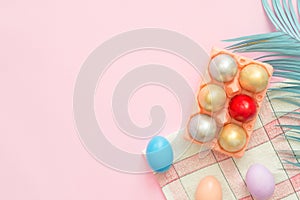 Flat lay top view colorful easter egg painted in pastel colors composition and spring flowers on pink pastel color background.