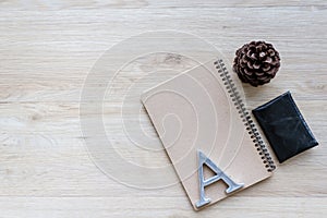 Flat lay, top view, desk, wood surface, pine cones, metal letters, A letter, H letter, S letter, black pencil, paper clip, wallet