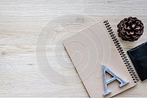 Flat lay, top view, desk, wood surface, pine cones, metal letters, A letter, H letter, S letter, black pencil, paper clip, wallet