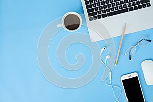 Flat lay top view mockup photo of working space with laptop, smart device and a cup of coffee on blue pastel background.