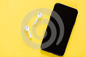 Flat lay top view mockup photo of working space with smartphone, headphones on yellow background. Back to school, online