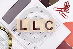 Flat lay, top view of office desk. Workplace with white calculator, magnifying glass, red paper clips and wooden cubes with text