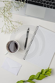 Workspace with blank clip board, laptop, office supplies, pencil, green leaf, and coffee cup on white background