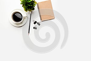 Flat lay, top view office table desk. Workspace with blank, office supplies, pencil, green leaf, and coffee cup on white