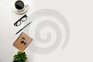 Flat lay, top view office table desk. Workspace with blank, office supplies, pencil, green leaf, and coffee cup on white