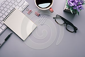 Flat lay, top view office table desk. Workspace with keyboard, office supplies, pencil, green leaf, and coffee cup on gray