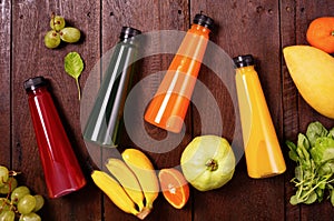 Flat lay top view orange, yellow, green, red juice bottles with banana, guava, spinach and mango on wooden table. Healthy lifestyl