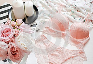 Flat lay. Top view pink lace lingerie. Beauty blog. Bouquet of roses and pions, parfume, jewelry, coffee on white bed background