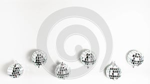 Flat lay top view silver mirror disco balls that spin on white background at the battom. Stop motion animation party concept