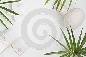 Flat lay top view spa background: thai massage bag, towels and palm leaves on white background. Healthy lifestyle