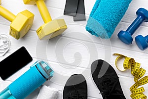 Flat lay top view sport equipments, sneakers and smartphone on white wooden background