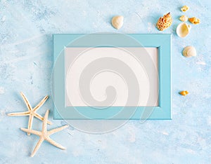Flat lay top view Summer vacation mockup: photo frame, seashells and white starfish on blue background. Travel, beach concept