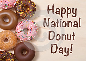 Donuts on table with Happy National Donut Day text photo