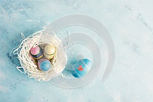 Flat lay top view white paper nest with three vintage Easter eggs and one blue egg with red heart on blue background