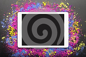 Flat lay of touchpad with blank screen with colorful cosmetic powder on black background
