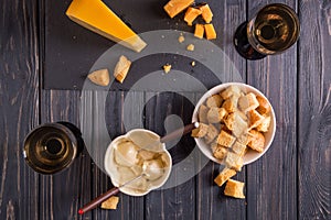 Flat lay. Traditional french cheese fondue. Crouton dipped into hot cheese fondue on a long-stemmed fork.