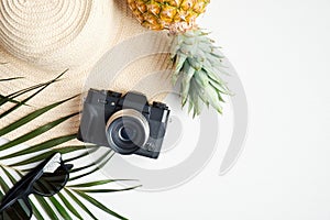 Flat lay traveler accessories with tropical palm leaf branches on white background. Top view beach straw hat, vintage style camera