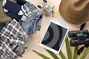 Flat lay travelling set with spinning of fishing tools, binoculars, hat, man cloths and gadget on pastel background. travel