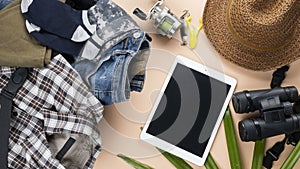 Flat lay travelling set with spinning of fishing tools, binoculars, hat, man cloths and gadget on pastel background. travel