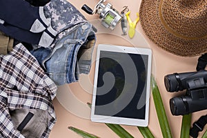 Flat lay travelling set with spinning of fishing tools, binoculars, hat, man cloths and gadget on pastel background. travel